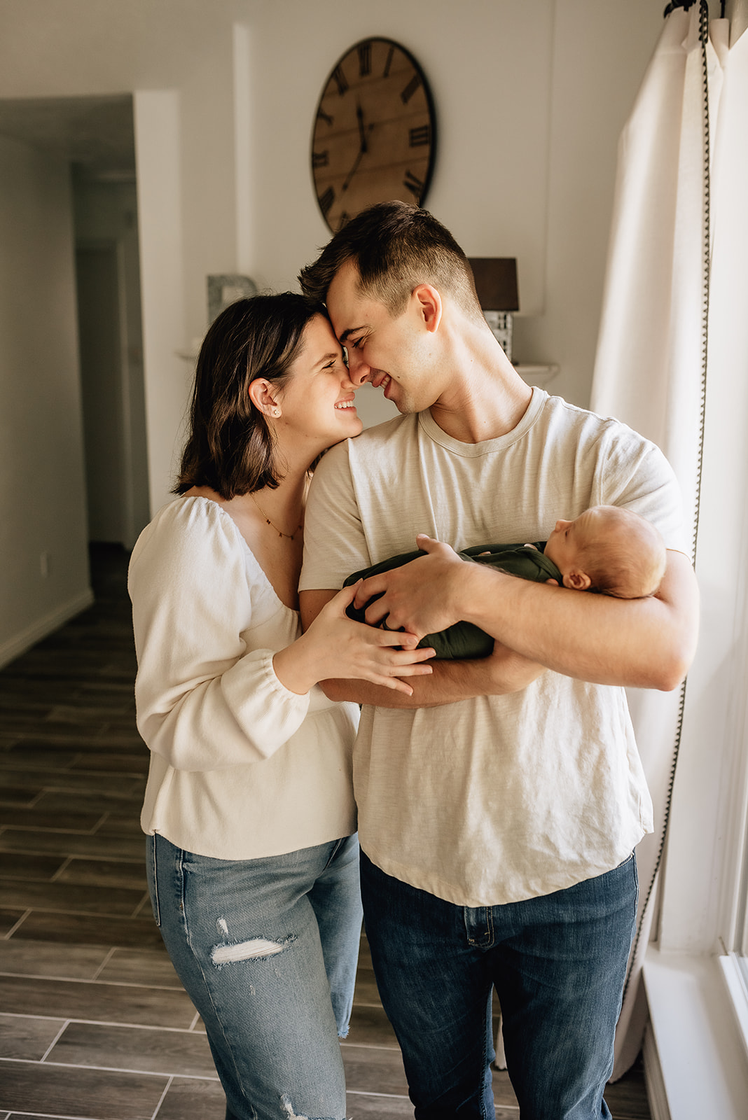 New parents press their foreheads together while dad cradles their newborn baby against his chest Midwife in The Heights
